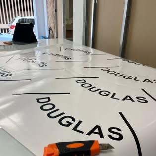 Cut vinyl lettering for the yacht name 'Douglas' being weeded on the workshop bench